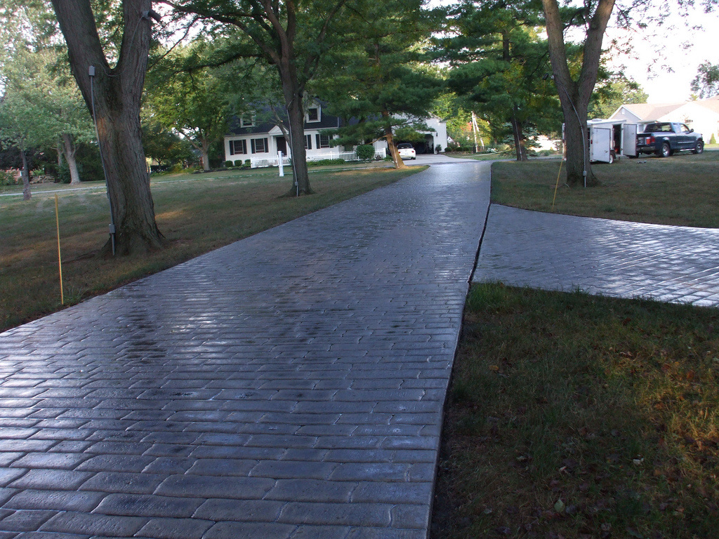 Long driveway with a gray stamped concrete design. 